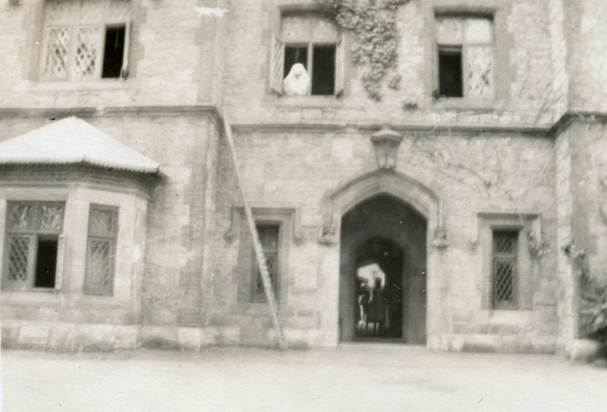Black and white photograph of old hospital building with ghost like figure in window.