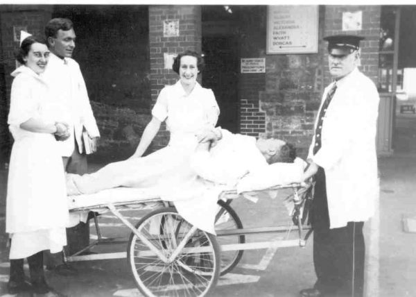 patient surrounded by nurses laying on a barouche or patient trolley.